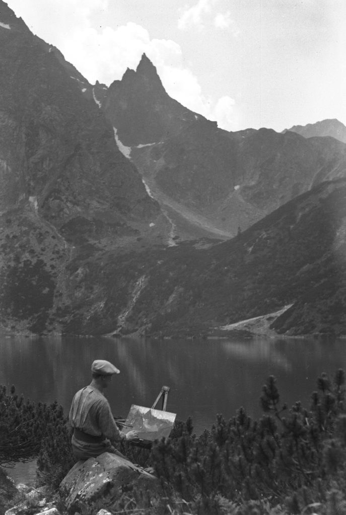 Widok na Tatry i Morskie Oko. Na przodzie mężczyzna przy sztaludze maluje obraz, 1930, Narodowe Archiwum Cyfrowe